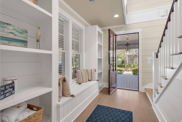 mudroom with wood walls and light hardwood / wood-style flooring