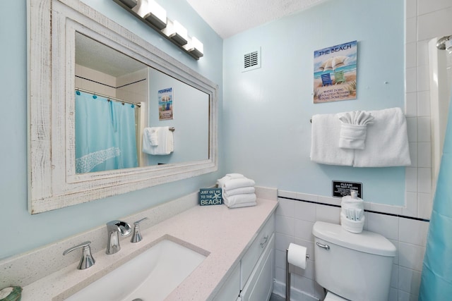 full bath featuring toilet, vanity, visible vents, tile walls, and a shower with curtain