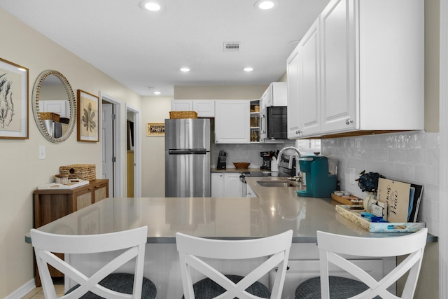 kitchen with sink, white cabinetry, tasteful backsplash, appliances with stainless steel finishes, and kitchen peninsula