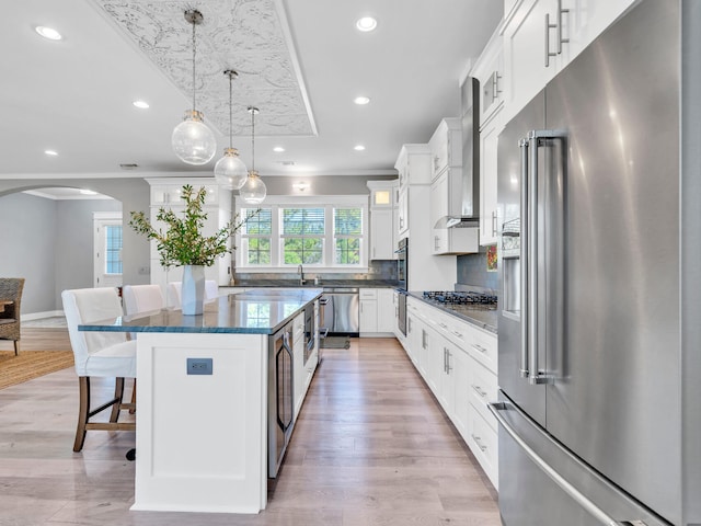 61 Sweet Breeze Dr, Santa Rosa Beach, FL 32459 - kitchen featuring stainless steel appliances, wall chimney exhaust hood, a kitchen bar, arched walkways, and a center island