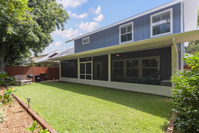 rear view of house featuring a yard and a sunroom