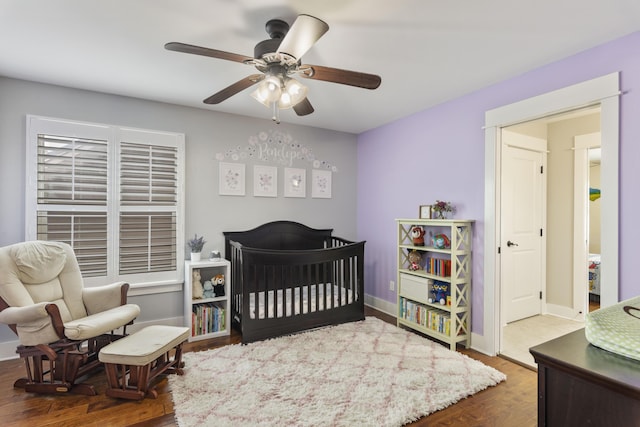 bedroom featuring ceiling fan, dark hardwood / wood-style floors, and a nursery area