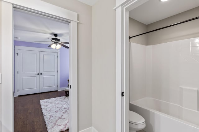 bathroom with ceiling fan, washtub / shower combination, wood-type flooring, and toilet