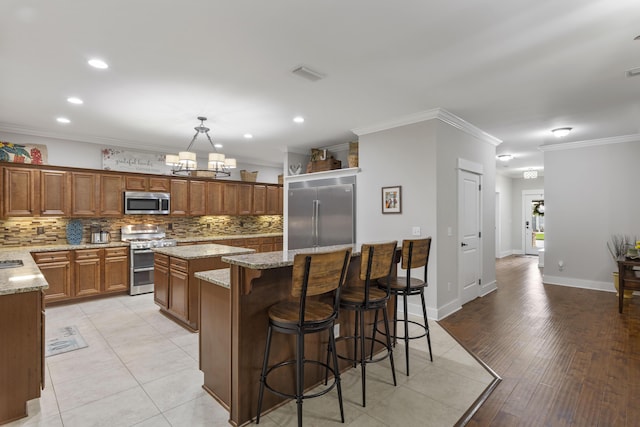 kitchen featuring a kitchen island, appliances with stainless steel finishes, pendant lighting, and decorative backsplash