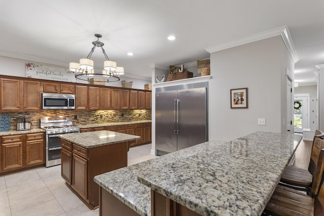 kitchen with pendant lighting, ornamental molding, stainless steel appliances, and a center island