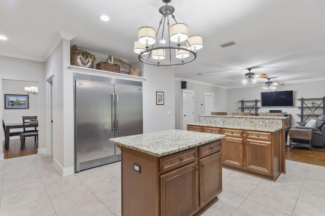 kitchen with pendant lighting, ornamental molding, a center island, and built in refrigerator