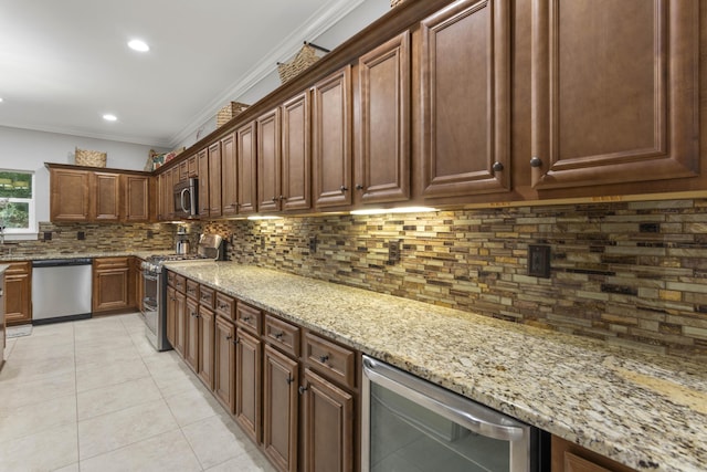 kitchen with light stone counters, light tile patterned floors, crown molding, and appliances with stainless steel finishes