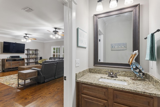 bathroom with crown molding, ceiling fan, vanity, and hardwood / wood-style floors