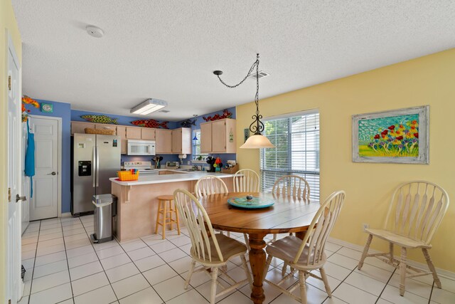 dining space featuring sink, a textured ceiling, and light tile patterned floors