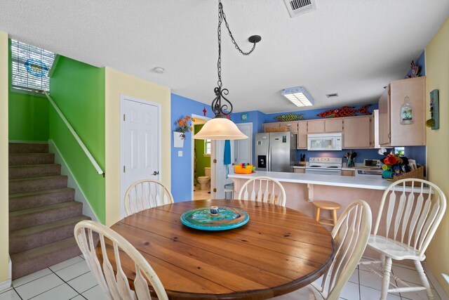 tiled dining room featuring a textured ceiling