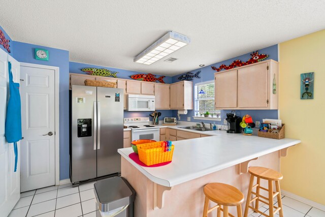 kitchen featuring light tile patterned flooring, light brown cabinets, white appliances, and kitchen peninsula