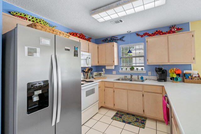 kitchen with white appliances, light tile patterned floors, a textured ceiling, light brown cabinetry, and sink