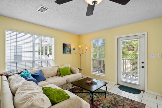 tiled living room with ceiling fan and a textured ceiling