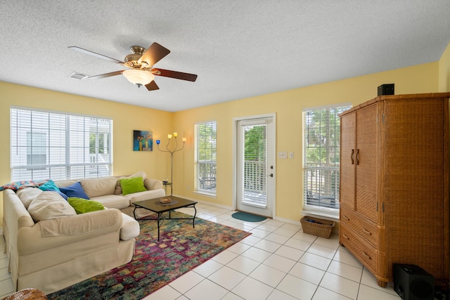 tiled living room with ceiling fan, a textured ceiling, and a wealth of natural light