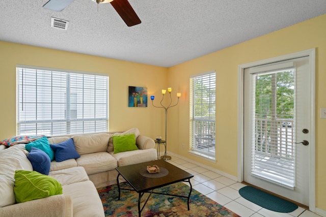 living room with ceiling fan, a textured ceiling, and light tile patterned floors