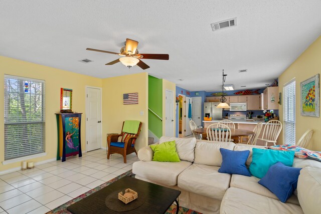 living room with a textured ceiling, light tile patterned floors, and ceiling fan