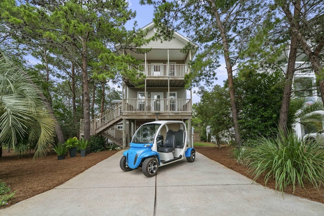 coastal inspired home with a balcony, a porch, and a carport