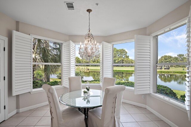 tiled dining room with a water view, a chandelier, and a healthy amount of sunlight