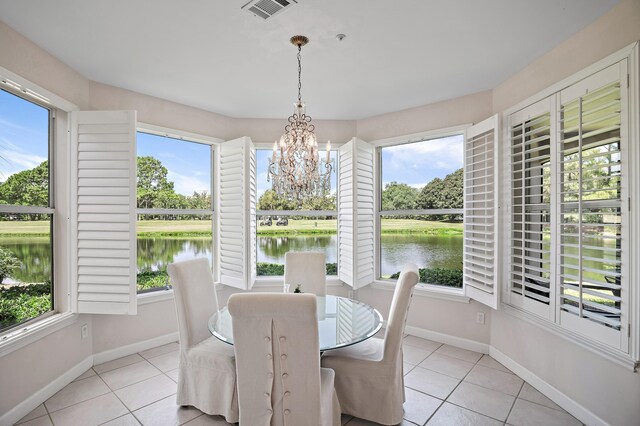 tiled dining space with a water view, a chandelier, and a healthy amount of sunlight