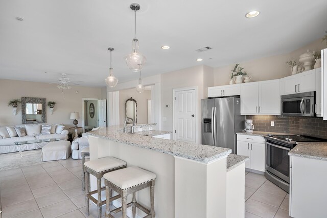 kitchen with white cabinets, stainless steel appliances, hanging light fixtures, and a kitchen island