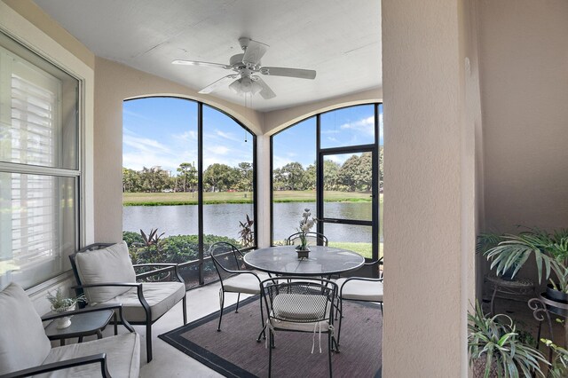 sunroom with a water view and ceiling fan