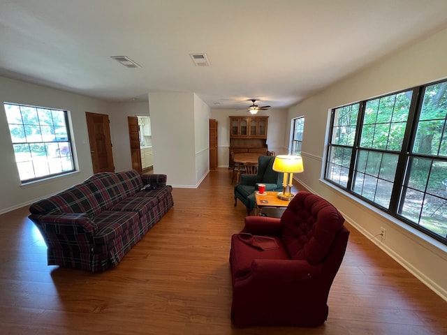 living room with a wealth of natural light, wood-type flooring, and ceiling fan