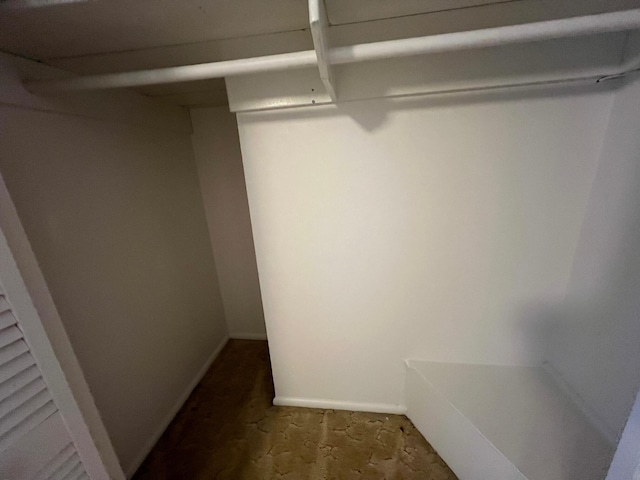 walk in closet featuring dark carpet