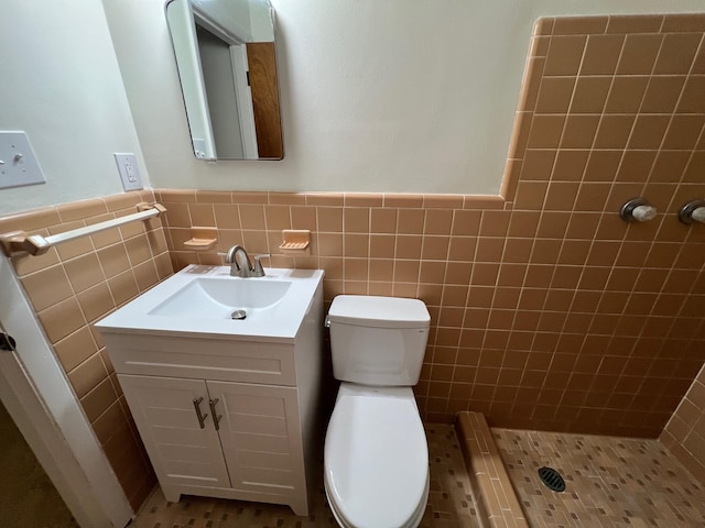 bathroom featuring vanity, a tile shower, tile patterned floors, and toilet