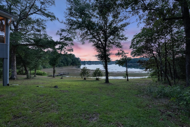 yard at dusk featuring a water view