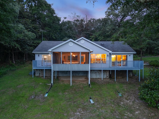 back house at dusk with a yard and a deck