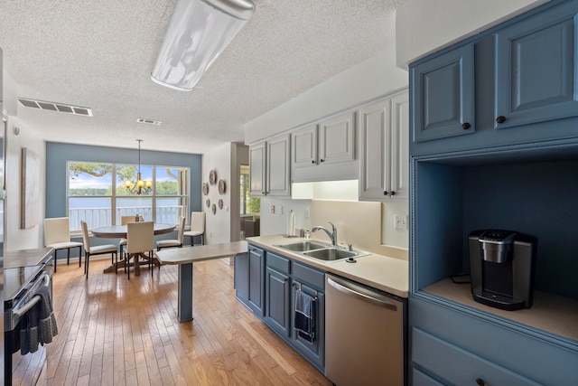 kitchen with appliances with stainless steel finishes, light hardwood / wood-style flooring, sink, a textured ceiling, and a notable chandelier