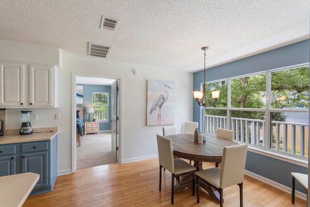 dining room featuring a textured ceiling, light carpet, an inviting chandelier, and a wealth of natural light