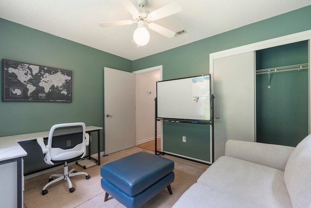 carpeted home office featuring ceiling fan