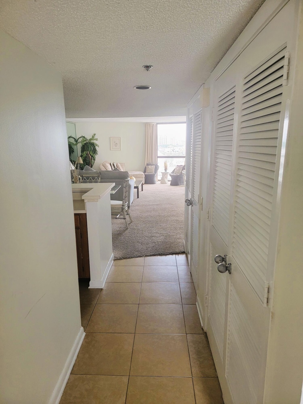 hall with light colored carpet and a textured ceiling