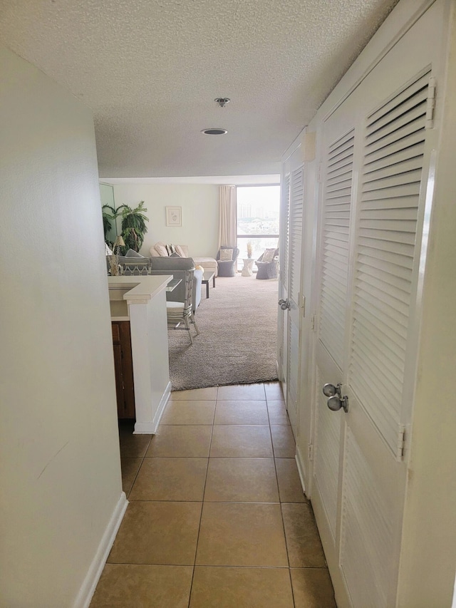 hall with light colored carpet and a textured ceiling