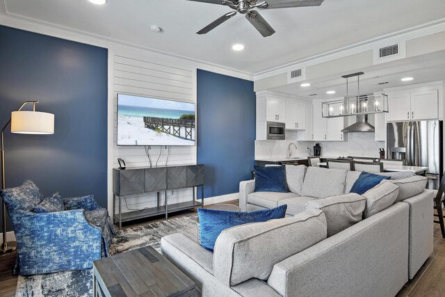 living room with ceiling fan, sink, dark hardwood / wood-style floors, and ornamental molding