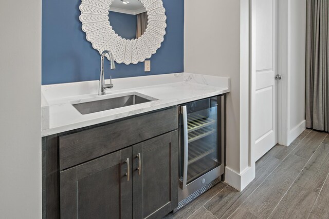 bar featuring sink, crown molding, dark brown cabinetry, and wine cooler