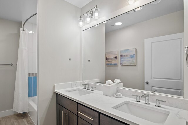 bathroom featuring dual vanity, hardwood / wood-style floors, and shower / bath combination with curtain