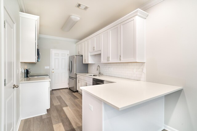 kitchen featuring sink, ornamental molding, kitchen peninsula, stainless steel appliances, and white cabinets