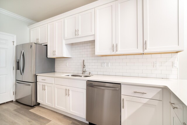 kitchen featuring appliances with stainless steel finishes, tasteful backsplash, sink, light wood-type flooring, and white cabinetry