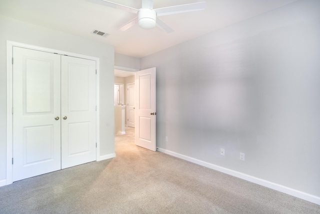 unfurnished bedroom with ceiling fan, light colored carpet, and a closet