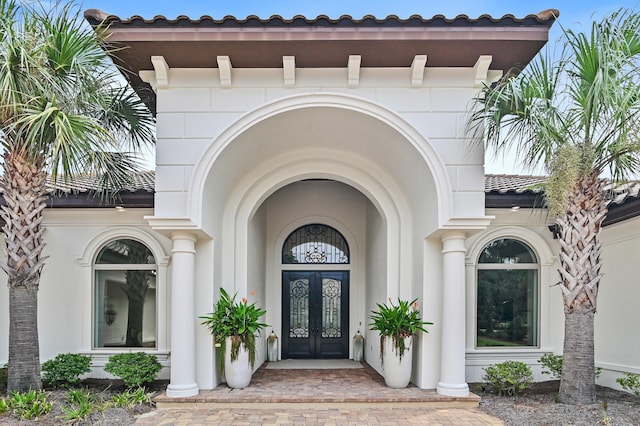 doorway to property with a tiled roof, french doors, and stucco siding