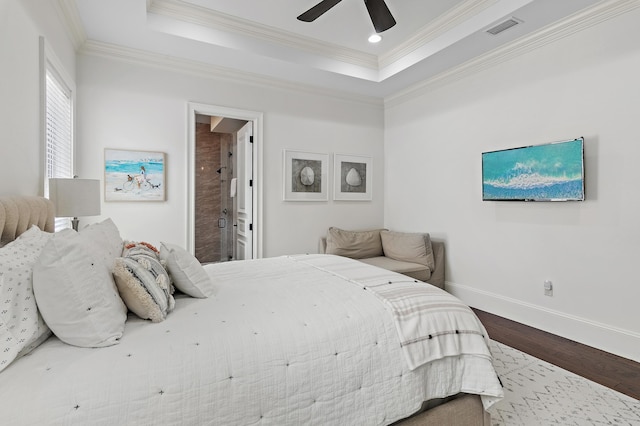 bedroom featuring baseboards, visible vents, a raised ceiling, ornamental molding, and wood finished floors