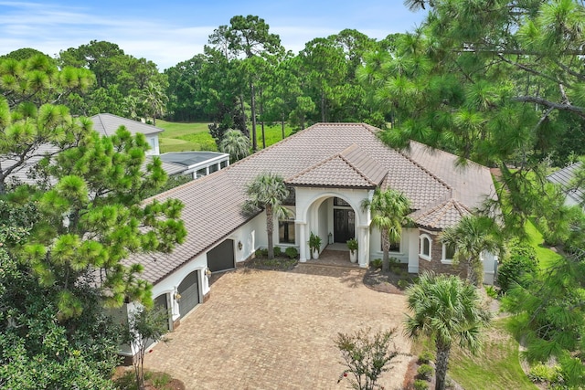 mediterranean / spanish-style home with decorative driveway, a tiled roof, and stucco siding