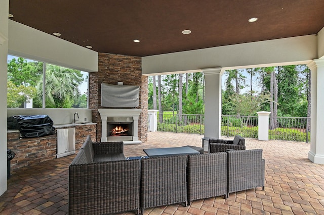 view of patio featuring exterior kitchen, fence, a sink, and an outdoor living space with a fireplace