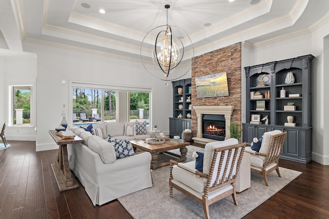 living area with a wealth of natural light, a raised ceiling, dark wood finished floors, and a stone fireplace