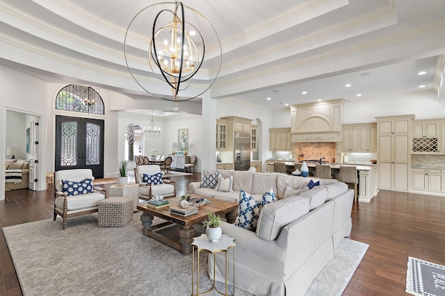 living room with a tray ceiling, french doors, a notable chandelier, and arched walkways