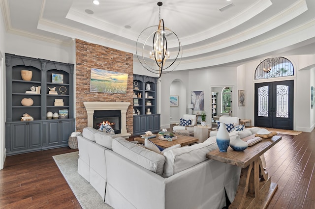 living area featuring built in shelves, a tray ceiling, french doors, dark wood-type flooring, and a chandelier