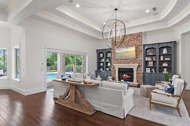 living room featuring dark wood-style floors, a fireplace, a tray ceiling, and a chandelier