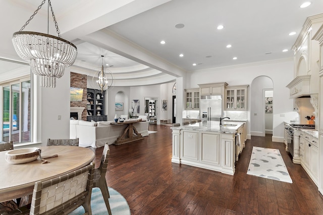 kitchen featuring glass insert cabinets, arched walkways, cream cabinetry, and high quality appliances